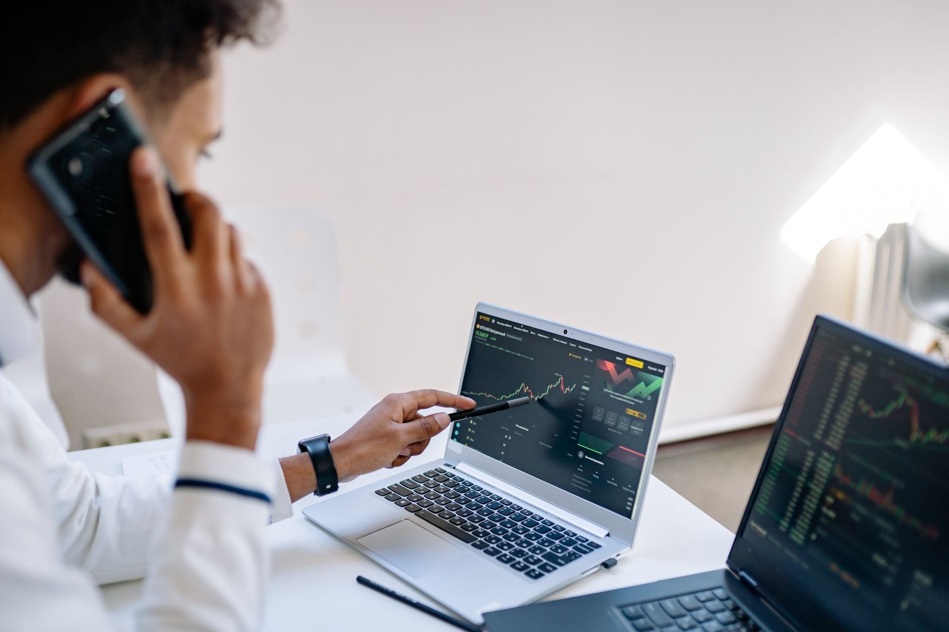 Business professional analyzing financial charts on laptops in office setting.